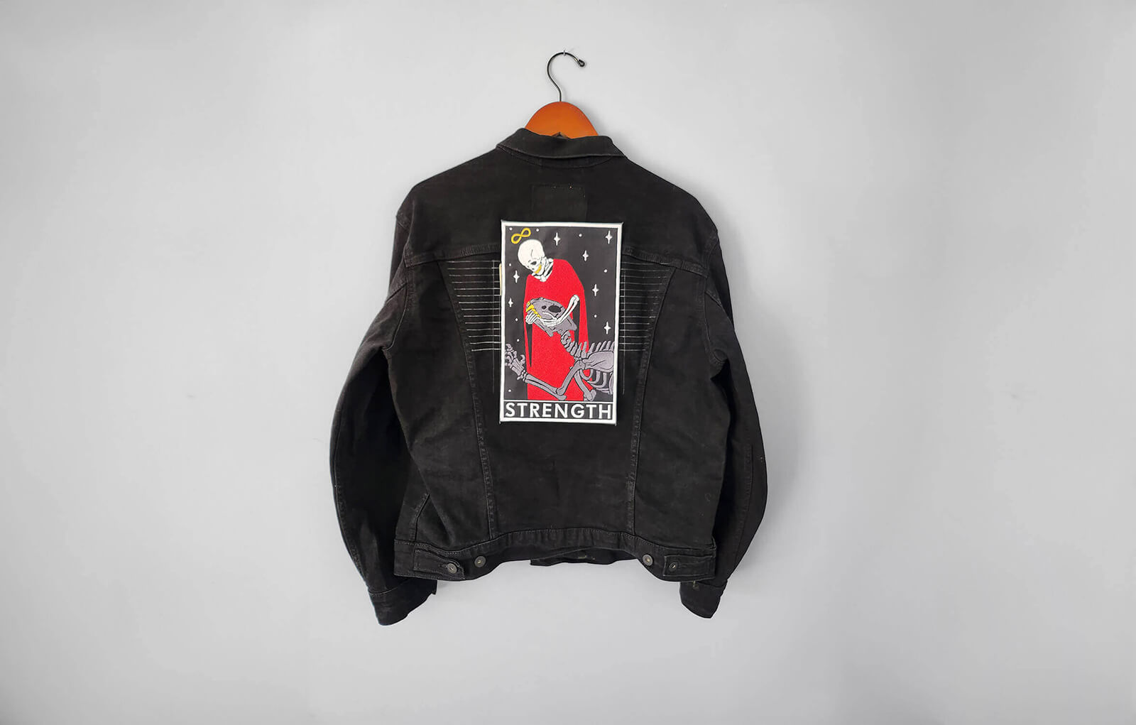 An embroidered patch of the courage card on a black denim jacket